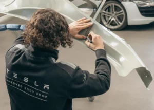 Technicien Tesla posant une pièce de carrosserie – Carrosserie Tropea à Chambéry