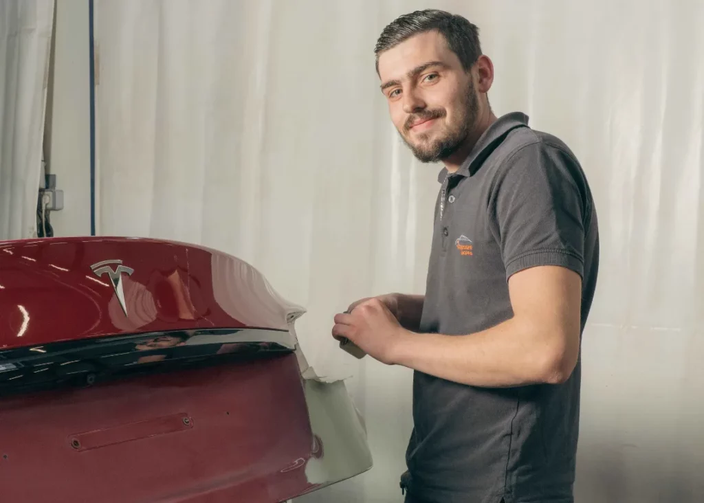Carrossier contrôlant la carrosserie d'un véhicule rouge – Carrosserie Tropea à Chambéry