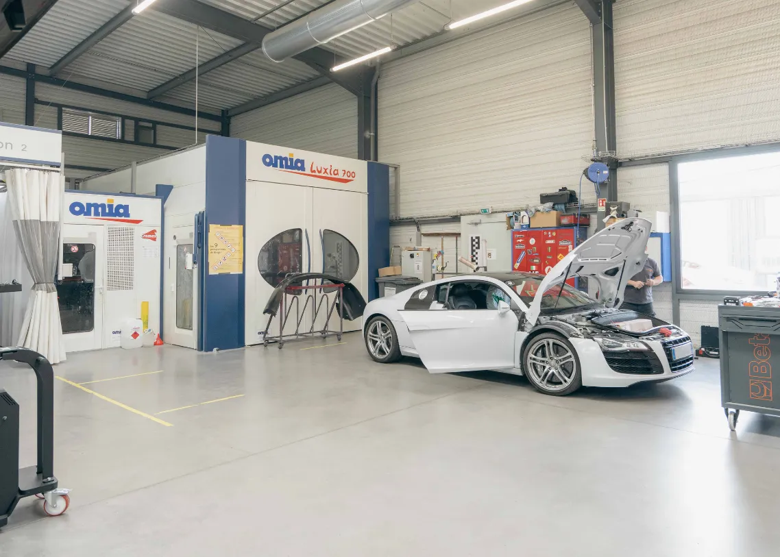 Cabine de peinture et Tesla blanche dans l'atelier – Carrosserie Tropea à Chambéry